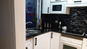 A modern kitchen with white cabinets, a black countertop, a built-in oven, and a microwave. - Disabled friendly - LUXURY bungalow / Villa , San Eugenio,  Costa Adeje  (Costa Adeje)