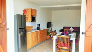 A compact kitchen with a refrigerator, microwave, and coffee maker. There is a dining area with a table and chairs. - ❤F2 luxury, sea view, 2 min from beaches, quiet, nature, wifi, air conditioning (Les Anses-d'Arlet)