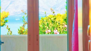 A room with a bed, a window with a view of mountains and a body of water, and a curtain. - Large group villa with pool, in Attica, Marathon, Sesi beach (Marathon)