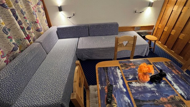 A cozy room with a sofa, a wooden chair, a small table, and a TV mounted on the wall. - Les Arcs 1800: studio - 1 room - 4/5 persons (Bourg-Saint-Maurice)