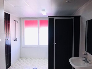 A bathroom with a shower, a sink, and a window. - Dongseoul Respia (Wonju)