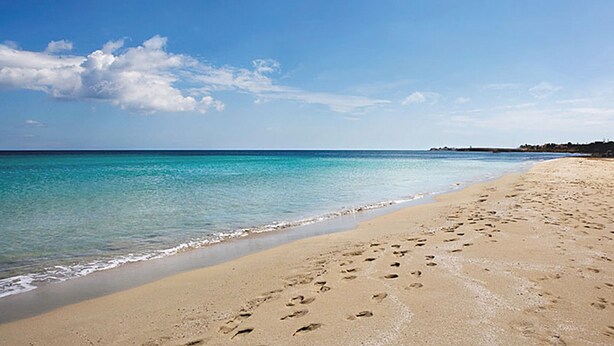 A beach with clear turquoise water, a sandy shore, and footprints in the sand. - Casa Palme, APARTMENT AT SEA (Marzamemi)