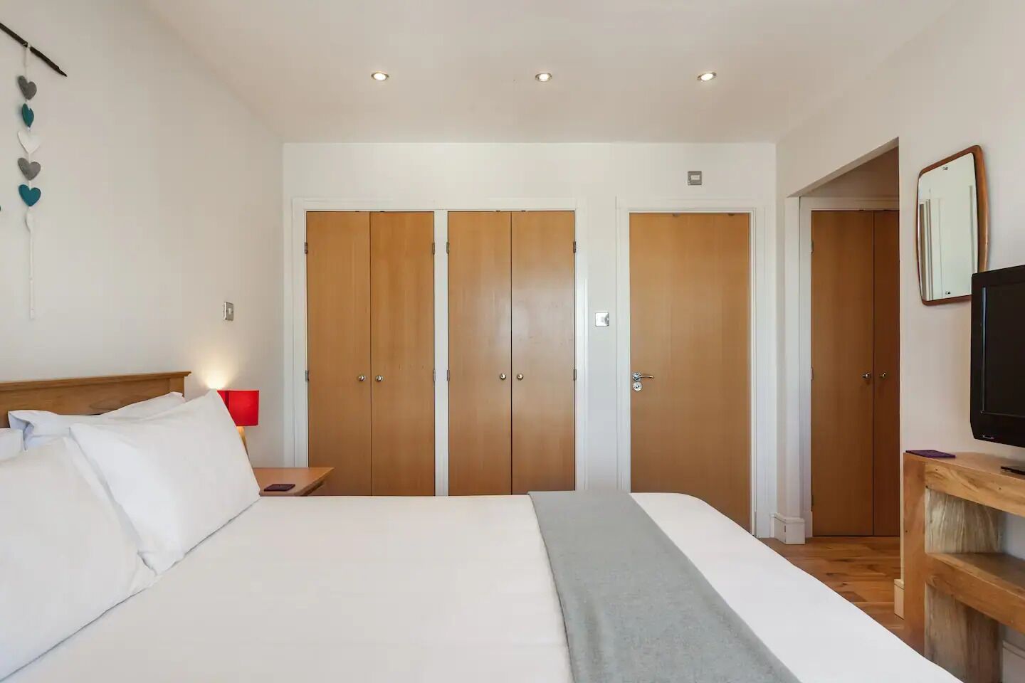 Habitació d'hotel amb un llit, una taula de nit, una televisió i un armari.