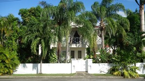 Ein Gebäude mit weißer Fassade, einem verschlossenen Eingang und üppiger tropischer Bepflanzung.