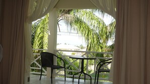 Ein Balkon mit Tisch und Stühlen, der auf einen Garten mit Palmen blickt.