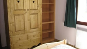 A bedroom with a wooden wardrobe, a bed, and a window with curtains. - Chimney sweep in the hamlet of La Chal (Saint-Jean-D'arves)