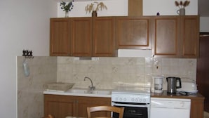 A small kitchen with wooden cabinets, a white stove, a sink, and a dishwasher. - Chimney sweep in the hamlet of La Chal (Saint-Jean-D'arves)