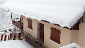 A snow-covered building with a balcony and wooden shutters. - Chimney sweep in the hamlet of La Chal (Saint-Jean-D'arves)