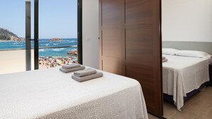 Un dormitorio con un amplio ventanal corredera que da a un balcón con vistas a la playa.
