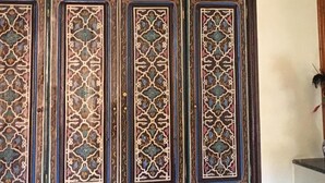 Una habitación con detalles de azulejos elaborados en las paredes y una lámpara colgante decorativa.
