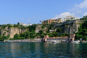 A coastal hotel with a cliffside location, multiple buildings, and a marina with boats.
