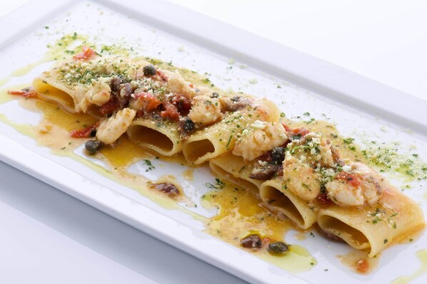 A dish of pasta with shrimp, olives, and herbs.