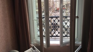 Ein Zimmer mit Blick auf eine Stadtansicht durch ein Fenster mit einem Metallbalkongeländer.