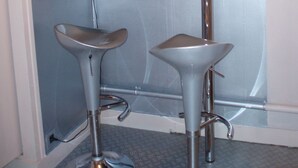 Eine Eckbar mit zwei Hockern, einem Spiegel und einer dekorativen Wandverkleidung.