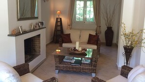 Ein Wohnzimmer mit Kamin, einer Couch, einem Couchtisch und einem Fenster mit Vorhängen.