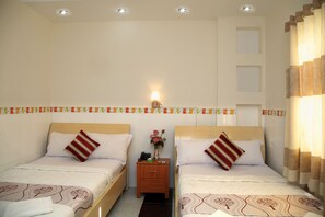 A hotel room with two single beds, a nightstand with a lamp, and a decorative wall panel.