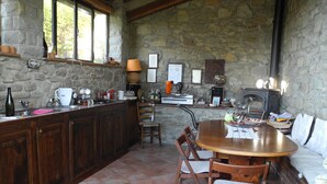 Una cocina rústica con paredes de piedra, armarios de madera y una gran mesa de comedor.