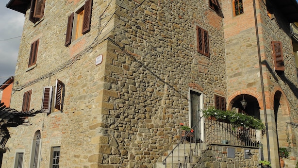 Un edificio de piedra con varias ventanas y una escalera que lleva a la entrada.