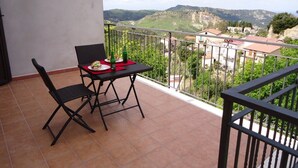 Un balcon avec une table et des chaises, donnant sur un paysage montagneux.