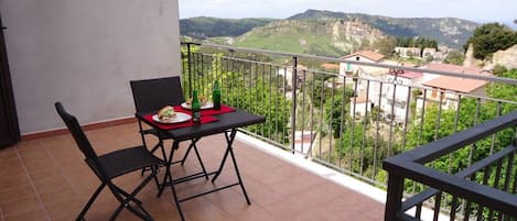 Un balcón con mesa y sillas, con vistas a un paisaje montañoso.