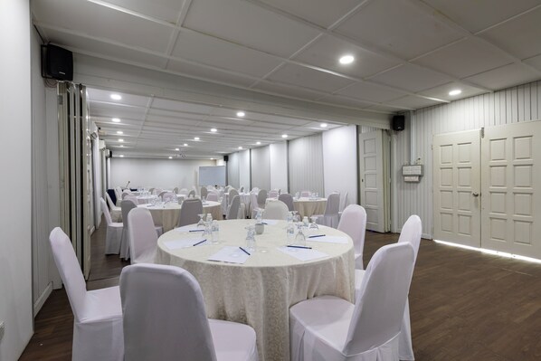 A conference room with round tables, white chairs, and a white ceiling.