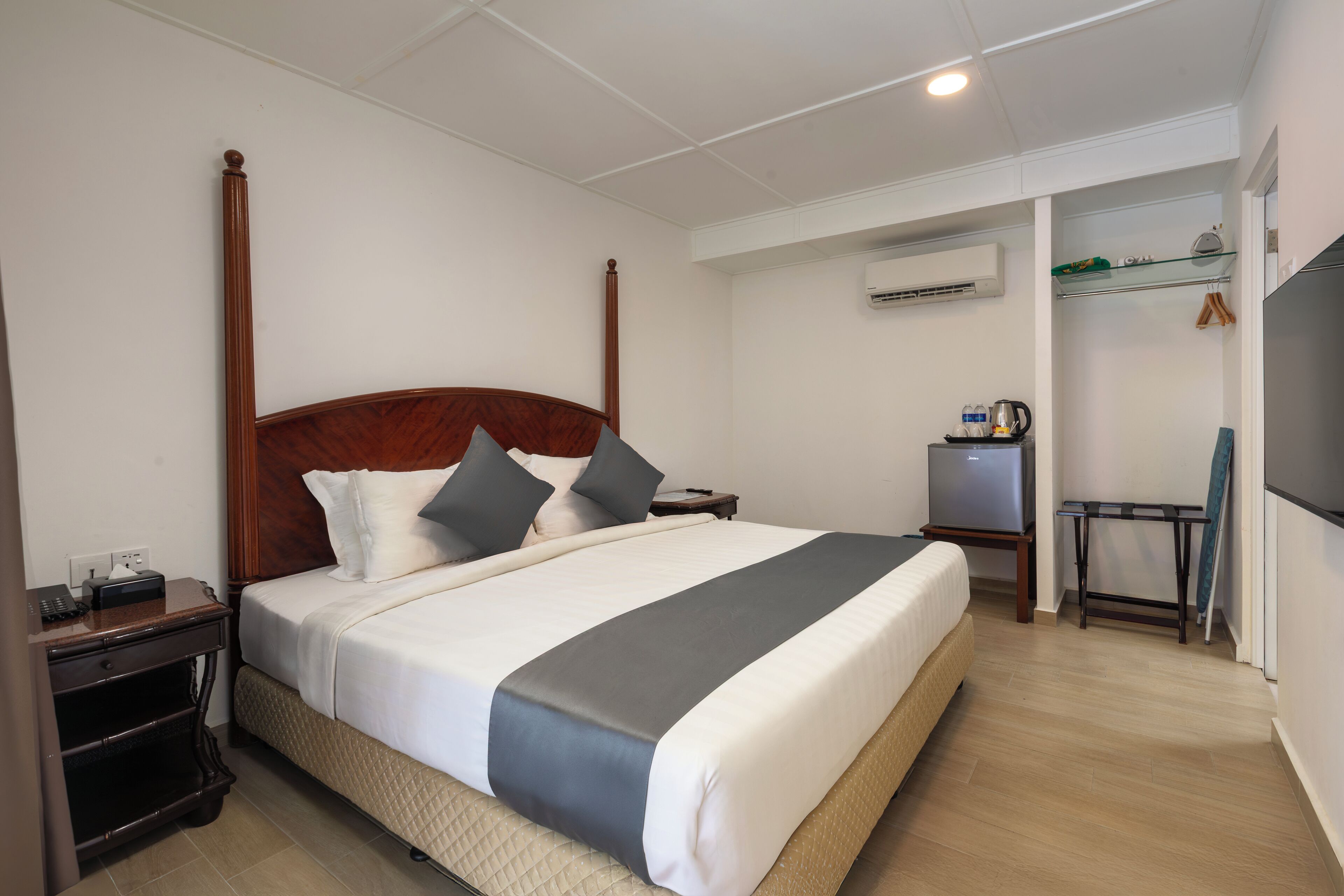 Une chambre d’hôtel avec un grand lit, une table de chevet, un appareil de climatisation, un petit bureau et un téléviseur.