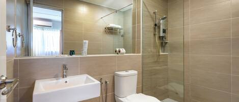 A modern bathroom with a glass-enclosed shower, a white sink, and a toilet.