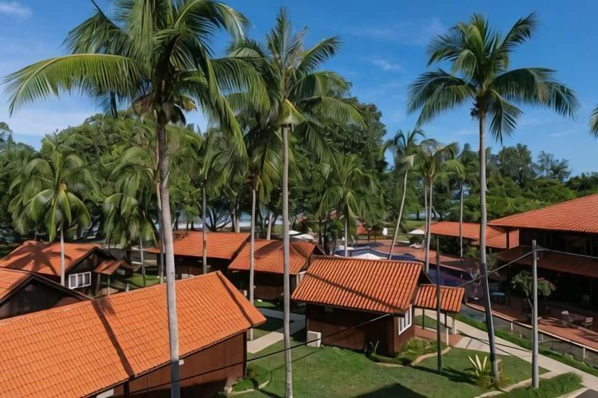 A resort with multiple bungalow-style buildings, palm trees, and a clear sky.