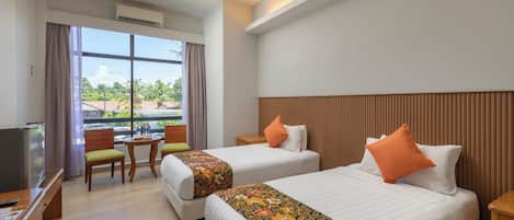 A hotel room with two beds, a desk, a chair, and a TV.
