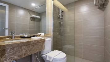 A modern bathroom with a glass-enclosed shower, a marble sink, and a toilet.