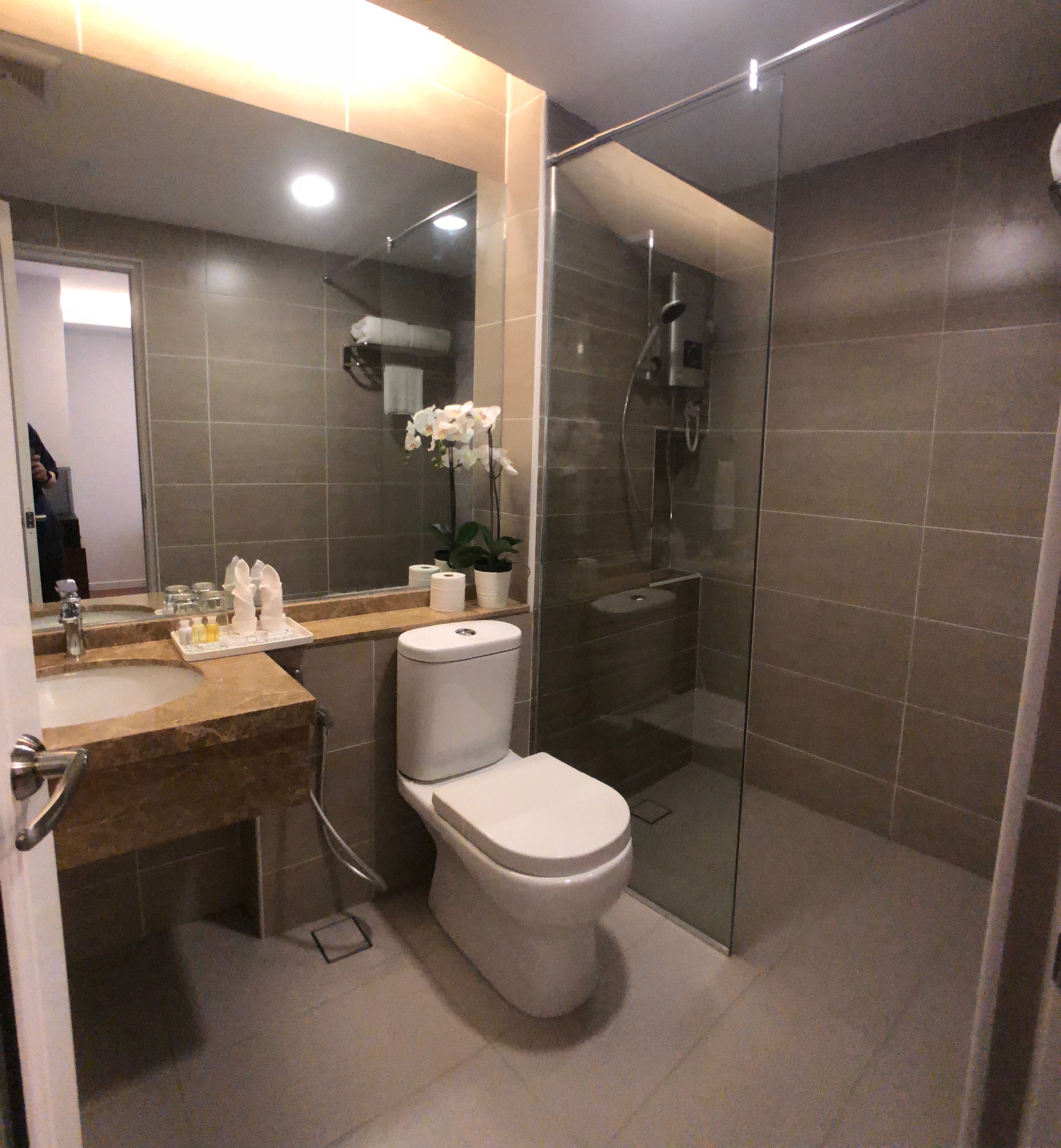 Une salle de bain moderne avec une douche à parois de verre, des toilettes et un lavabo équipé de produits de toilette.