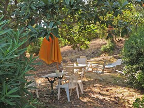 An outdoor seating area with tables and chairs, surrounded by trees and greenery. - 1st Floor Apartment With Beautiful Sea View in Magnificent Character Building (Cannes)