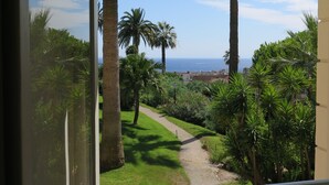 A balcony with a view of a garden path leading to a body of water. - 1st Floor Apartment With Beautiful Sea View in Magnificent Character Building (Cannes)