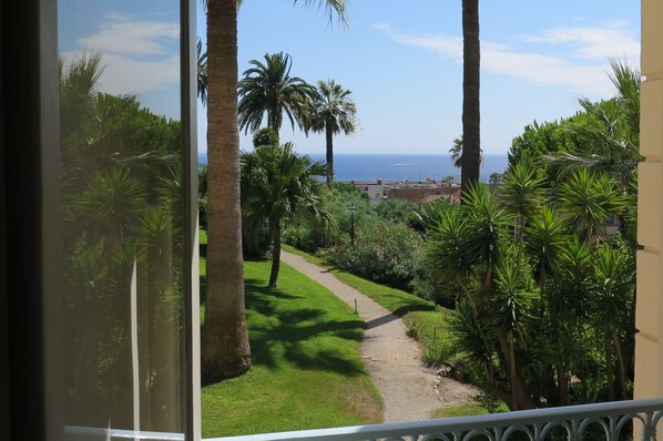 A balcony with a view of a garden path leading to a body of water. - 1st Floor Apartment With Beautiful Sea View in Magnificent Character Building (Cannes)