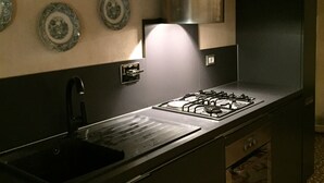 Eine Küche mit Gasherd, schwarzem Spülbecken und dekorativen Tellern an der Wand.