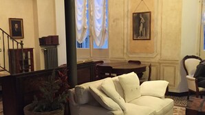 Ein Zimmer mit einer weißen Couch, einem Holztisch, einem Stuhl und einer Treppe.