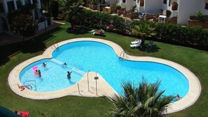 Une piscine en forme de cœur, entourée d’une pelouse bien entretenue et de palmiers.