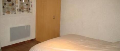 Quarto com cama, guarda-roupa de madeira e radiador.