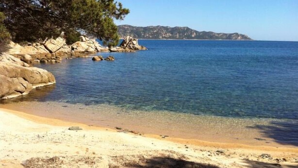 A beach with clear water, rocky outcrops, and a distant mountain range. - Punta Molara just 250 meters from the sea (San Teodoro)