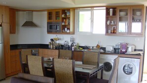 Une cuisine compacte équipée d’un four à micro-ondes, d’un évier et d’un lave-linge. On y trouve des chaises en osier et une table à manger.