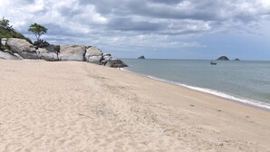 Une plage de sable avec de gros rochers et une mer calme.