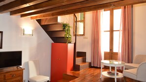 Un salon équipé d’un téléviseur, d’un meuble rouge, d’un escalier et d’un coin repas avec une table et des chaises.