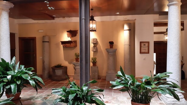 Un hall d’entrée spacieux, doté d’un sol carrelé, de grands pots de plantes et d’une colonne en pierre.