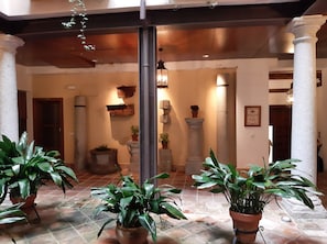 A spacious lobby with a tiled floor, large potted plants, and a stone column. - Welcome to the Historic Center of Toledo. Enjoy it (Toledo)