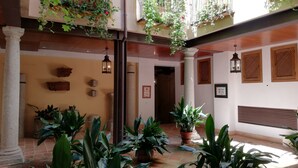 Une cour avec des plantes en pot, un sol carrelé et un banc en bois.