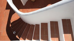 A spiral staircase with red tiles and white walls. - This large, family-friendly house is very peaceful and has separate bedrooms. (Cala Saona)