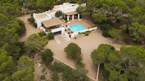An aerial view of a modern house with a swimming pool, surrounded by dense greenery. - This large, family-friendly house is very peaceful and has separate bedrooms. (Cala Saona)