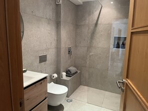 Een bad/douchecombinatie, een haardroger, een bidet, handdoeken