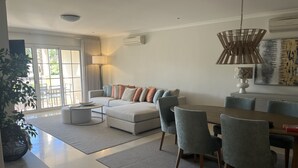 Ein modernes Wohnzimmer mit Sofa, Couchtisch und Essbereich.