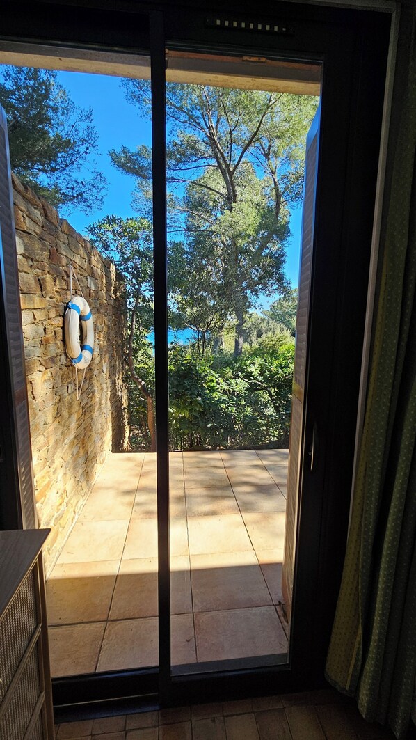 A sliding glass door leading to an outdoor patio with a stone wall and a lifebuoy.